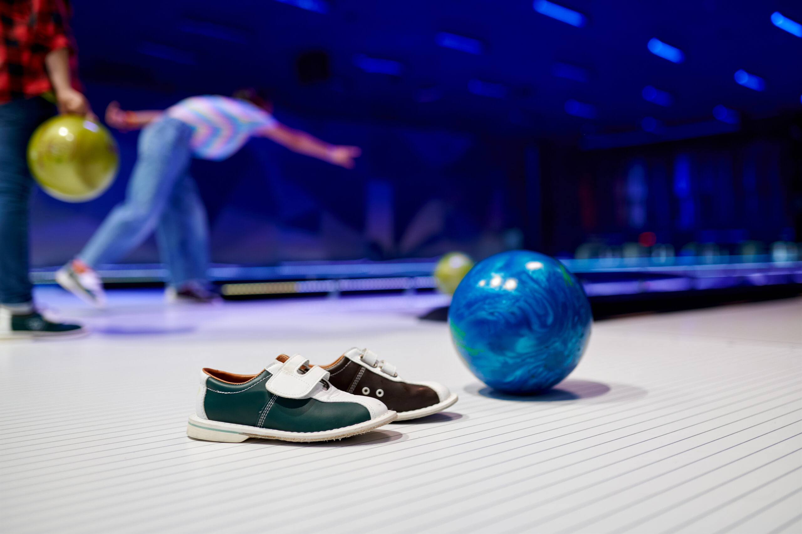 Ball and house shoes, children playing bowling, game concept. Kids are preparing to score a strike. Boys and girls having fun in entertainment center together
